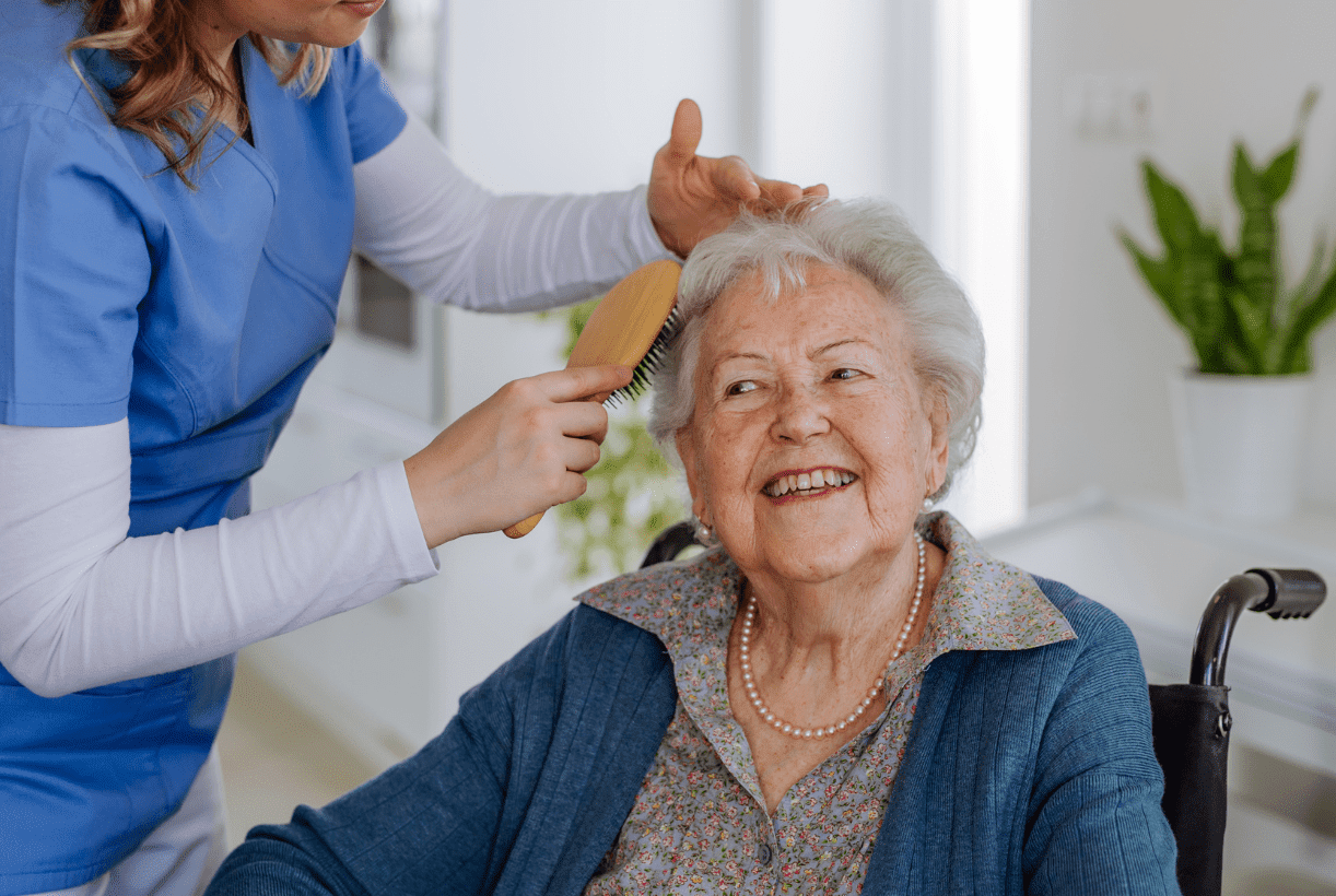 Caregiver gently brushing an older adult's hair while providing personal care and companionship at home in Lansing, Michigan.