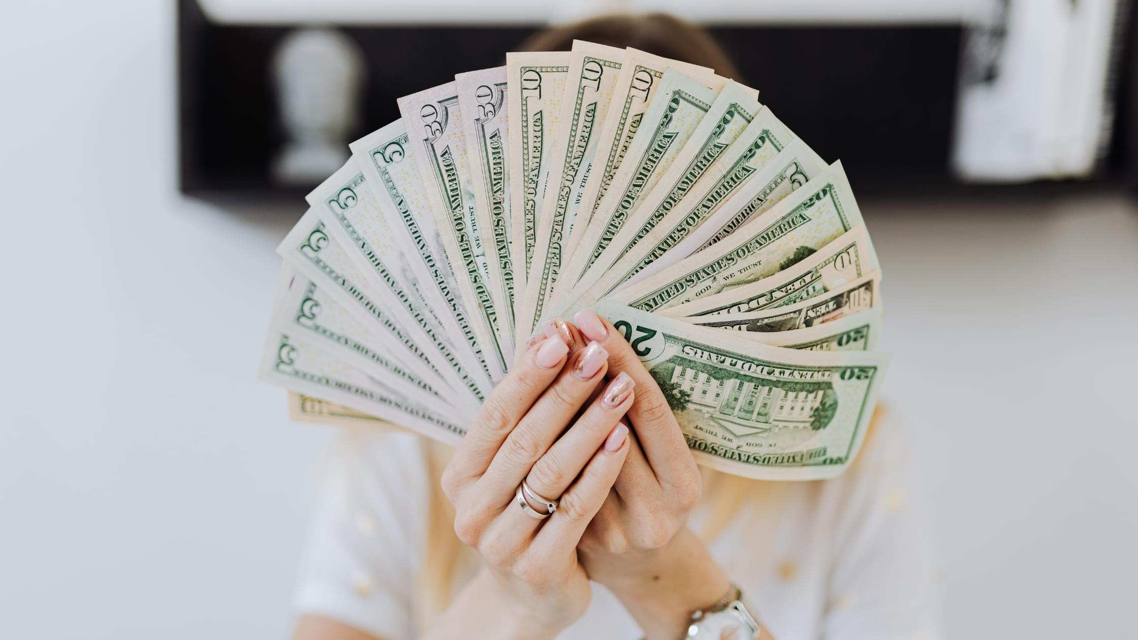 Person holding cash representing the Home Care Alternatives caregiver referral program in Lansing, Michigan, where you can earn $300 for referring a caregiver.