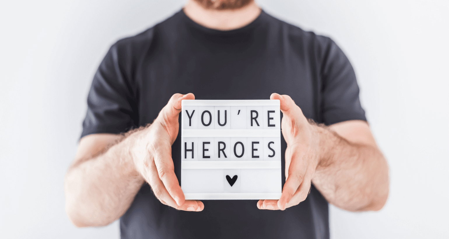 National Caregiver Appreciation Month graphic showing a sign that reads, "You're Heroes," thanking caregivers for their dedication.
