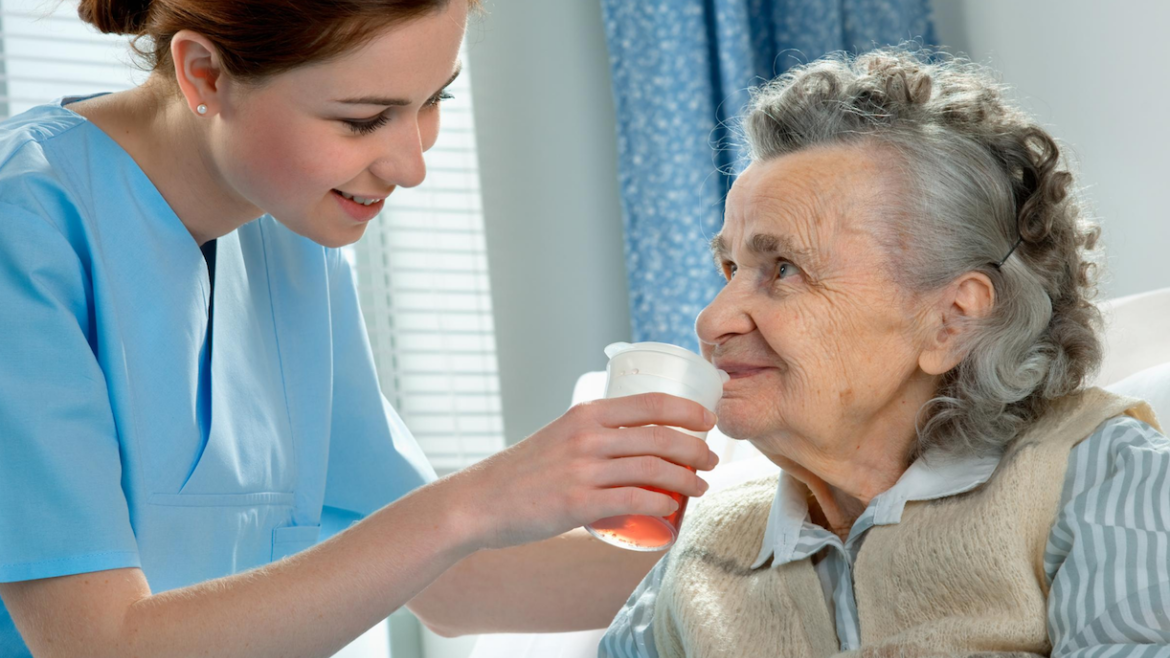 Compassionate caregiver assisting an older adult with hydration and personal care services in Lansing, Michigan.
