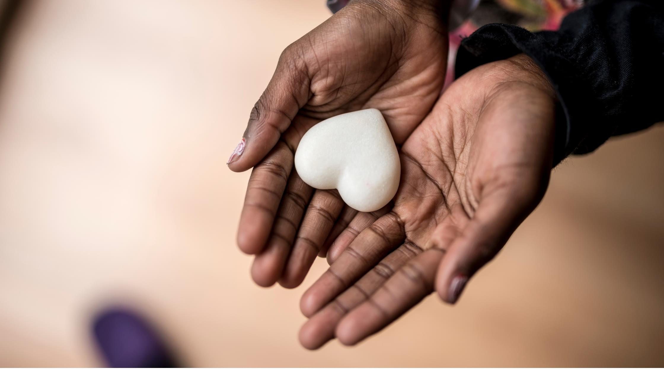 Hands holding a heart-shaped stone representing compassion and the emotional support involved in caring for aging parents.