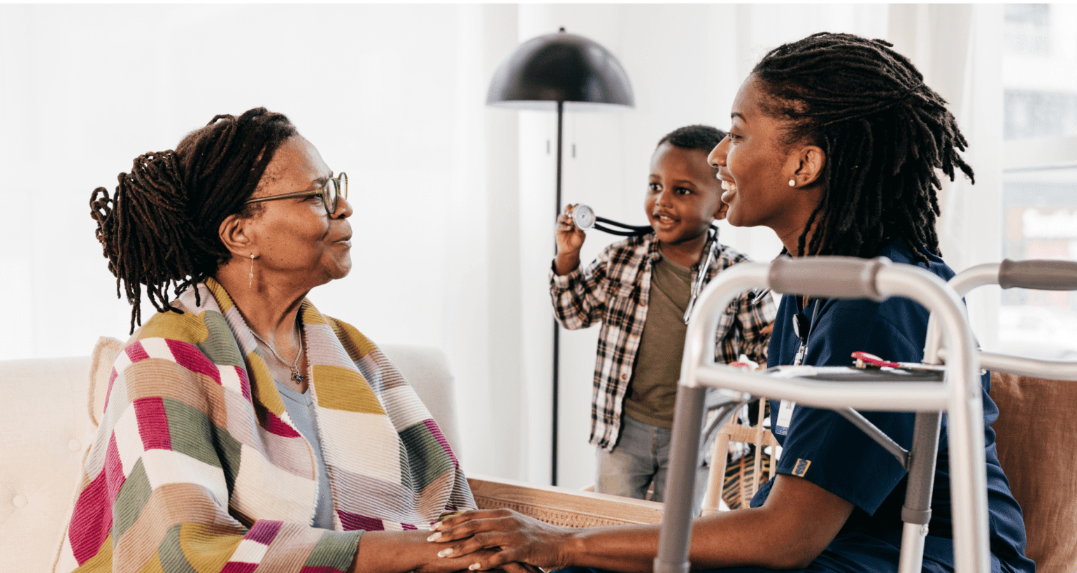 Professional caregiver providing compassionate in-home care while visiting with an older adult and family member in Lansing, Michigan.